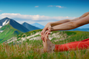 Closeup photo of young barefoot girl stretching body on green meadow in summer mountains, Sculpting...