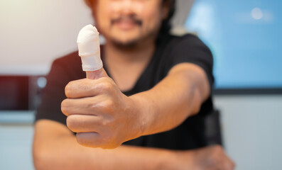 Men's hand has been injured by the accident and showing thumb up with a bandage.