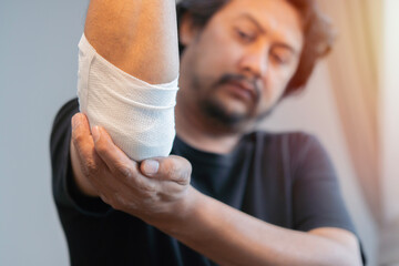 Selective focus of a white bandage wrapped on injured elbow.  First aid