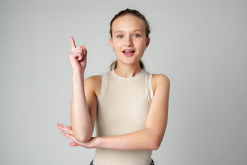 Young Woman Gesturing With One Finger Up Against a Grey Backdrop