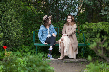 Best friends talking and sitting on a park bench outdoors - 793647414