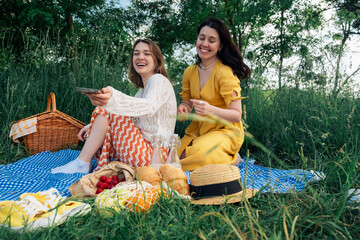 Two young women on a blue blanket outdoors on a picnic