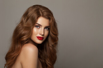 Perfect fashionable redhead woman with long wavy hair and make-up. Studio headshot portrait of fashion model lady with red colorful shine lipstick. Haircare, skin care and coloration concept