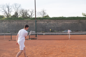 Young men playing tennis on an outdoor court