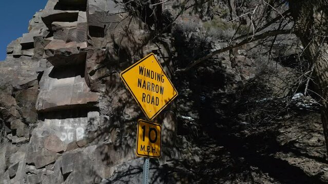 "Winding Narrow Road" sign along a high desert cliff road in the Rocky Mountains of the Western United States.  This sign is excellent as a metaphor for a large variety of things.