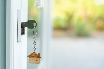 Landlord key for unlocking house is plugged into the door. Second hand house for rent and sale. keychain is blowing in the wind. mortgage for new home, buy, sell, renovate, investment, owner, estate - obrazy, fototapety, plakaty