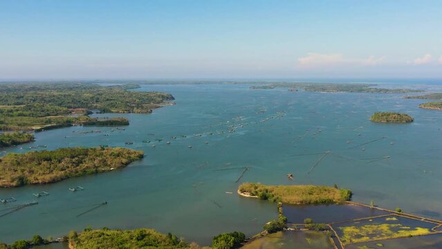 Aerial view of Auto feeding fish farming - breeding unit of sea bass and sea bream in huge round cages. Philippines, Luzon.