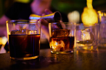 Glasses with ice into which the bartender pours