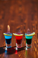 There are 3 tinctures of different colors with a slice of lemon and fire on the table