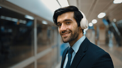 Closeup of smart business man wearing headphone and listening music while standing at train...