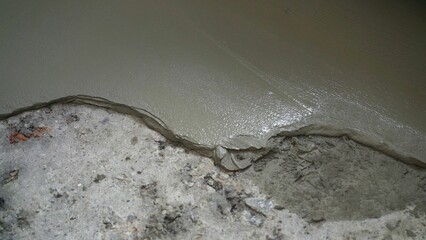 Close-up of a freshly poured concrete floor. Repair of self-leveling floor in an apartment. Fresh screed on the floor in the apartment, construction work and repairs. - obrazy, fototapety, plakaty