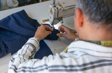 Man sewing a hem of pants with sewing machine