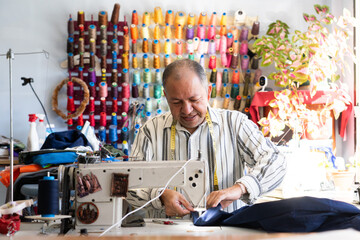 Latin seamstress man sewing with his sewing machine in his sewing workshop