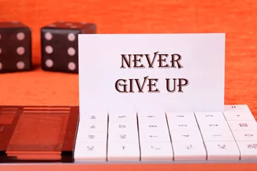 Foto op Canvas Never give up words on a white business card on a calculator on an orange background © Ihar