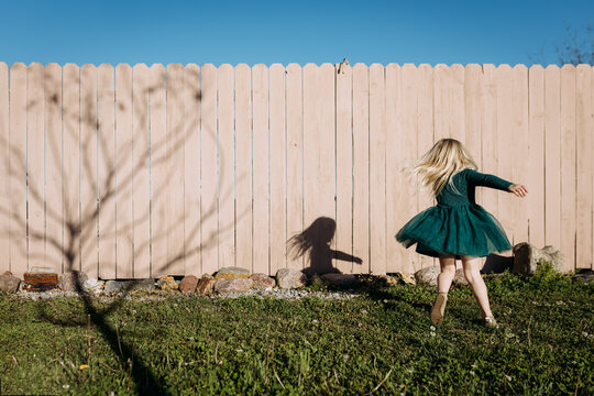 Young girl twirling in dress in yard on vibrant sunny day
