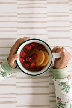 Toddler Drinking Winter Cider with Cranberries and Oranges