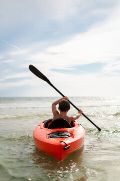 Child paddling a kayak in shimmering ocean waters