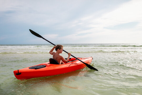 Boy with paddle on a kayak adventure at sea