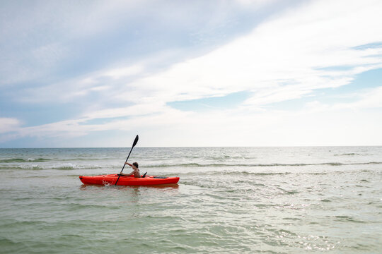 Child paddling in a kayak alone in a serene ocean setting
