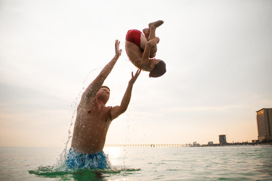 Joyful water play, child flipping in sunset ocean
