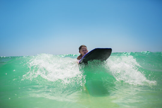Boy on a boogie board catching waves in clear sea