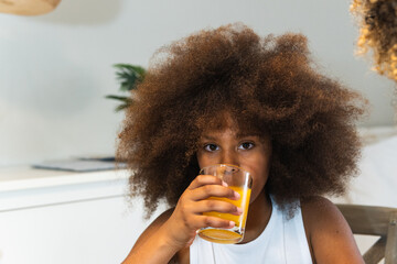 Young african american girl drinking a glass of fresh orange juice