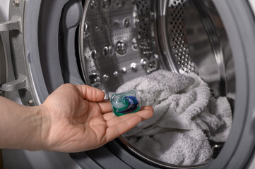Kapsułka do prania wkładana do pralki z białym ręcznikiem 
