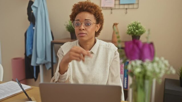 African american woman sitting on table showing middle finger, impolite and rude fuck off expression at home