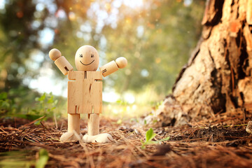 Wooden figure in nature with smiling face. Concept of joy happiness and wellness - 793672494