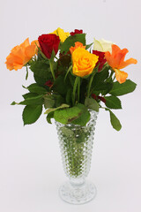 An image of a multicolored bouquet of roses in a glass vase. - obrazy, fototapety, plakaty