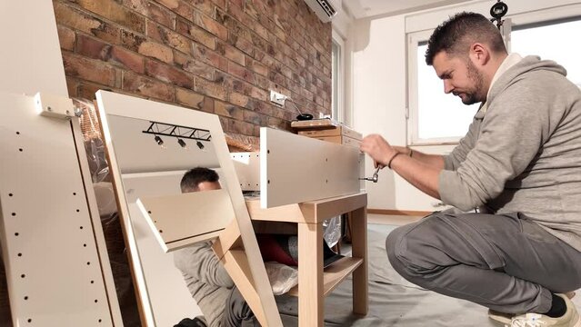 Man working and assembling furniture in a new apartment.