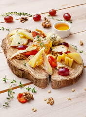 Cheese slices of different types of cheese with grapes, honey and nuts. Country style.