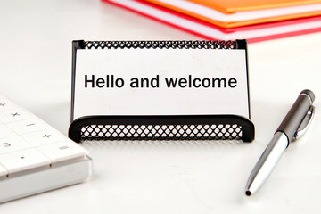 Hello & welcome text on a white business card next to a calculator, notepad and pen - obrazy, fototapety, plakaty