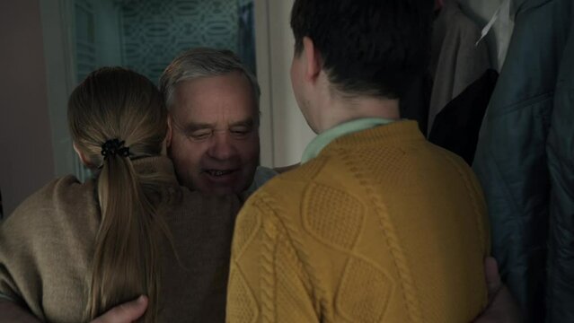 Elderly man meets his adult daughter at door. Son and daughter hug pensioner and smile at family reunion. Linking generations and caring for elderly parents.