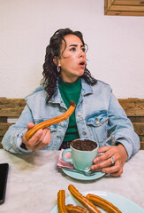 Arab woman caught eating chocolate with churros in Spain. Lifestyle, vertical image. - obrazy, fototapety, plakaty