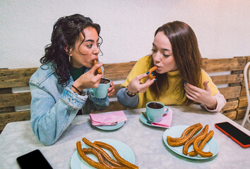 Two friends enjoy a fun snack, while chatting. Food and lifestyle concept. - obrazy, fototapety, plakaty