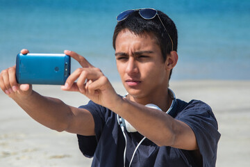 young man taking a selfie or live video with phone on the beach