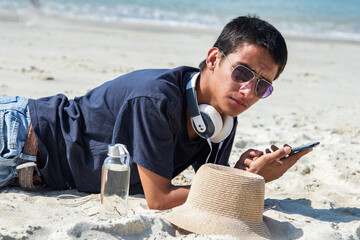 relaxed young man using phone on the beach