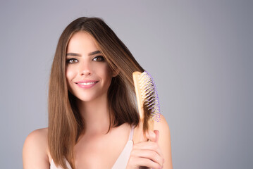 Girl combing hair with comb. Beautiful young woman holding hair comb. Female model hold comb near...