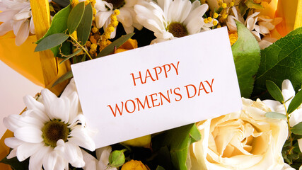 International Women's Day is celebrated on the 8th of March. Text HAPPY WOMEN IS DAY on a business card on a background of flowers - obrazy, fototapety, plakaty