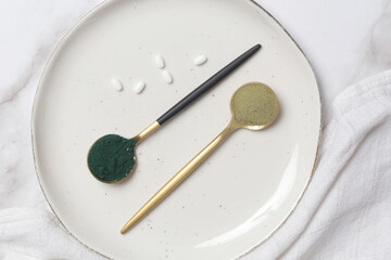 Green powder in the spoon, spirulina, alage, chlorophyll or matcha. Concept of nutritional supplement, dieting, detox, preventive healthcare and healthy lifestyle.