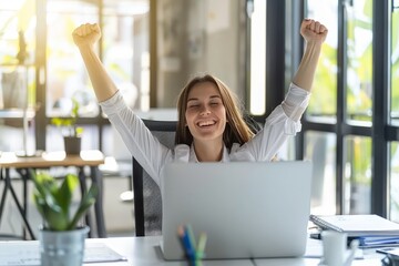 Successful businesswoman celebrating victory in front of laptop with arms raised in joy - obrazy, fototapety, plakaty