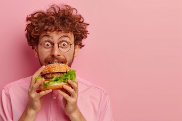 Man enjoying tasty burger in portrait against soft pastel background with space for text