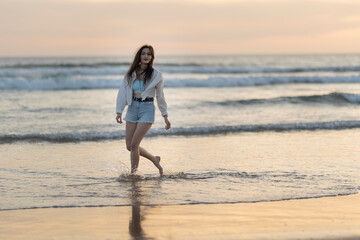 A woman is walking on the beach in the water