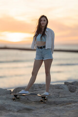 A woman is standing on a skateboard on a beach