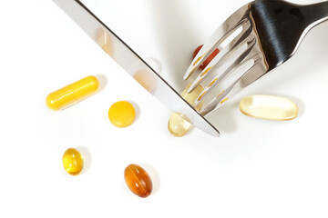 Eat omega 3 pills with fork and knife on a white background
