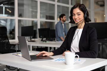 Happy smiling female customer support phone operator at workplace - 793702890