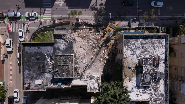 Aerial view of a demolished building with urban surroundings and excavator working on site