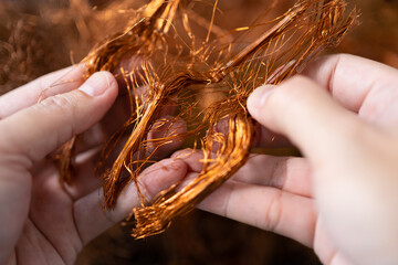 Man's hand holding copper wire for recycling