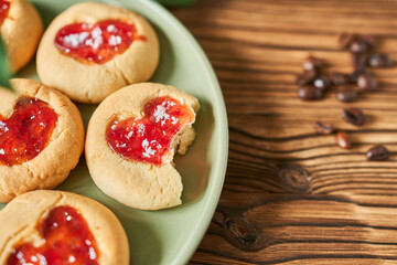 Cookies with strawberry jam on a plate on a wooden background.
